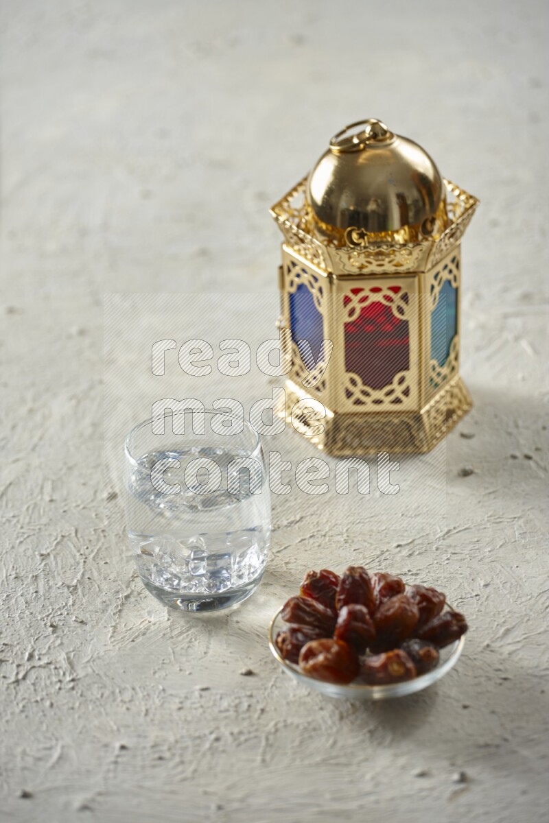 A golden lantern with different drinks, dates, nuts, prayer beads and quran on textured white background