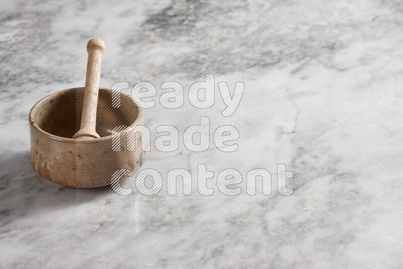 Beige pottery bowl with wooden honey dipper in it on grey marble background
