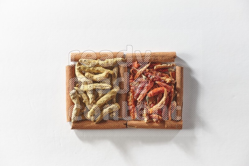 2 squares of cinnamon sticks full of dried red chilis and turmeric fingers on white flooring