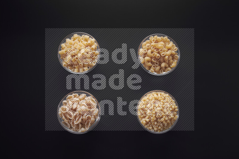 أنواع مختلفة من المعكرونة في وعاء زجاجي علي خلفية سوداء