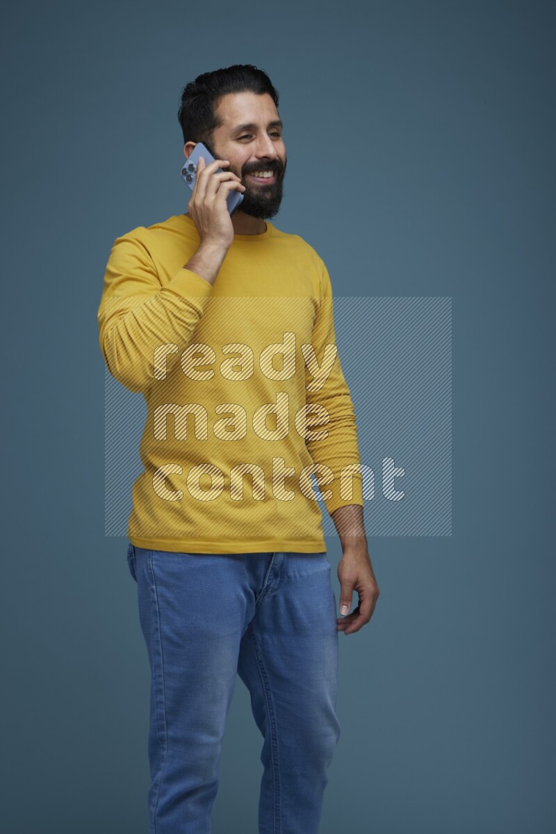 A man having a calling in a blue background wearing a yellow shirt