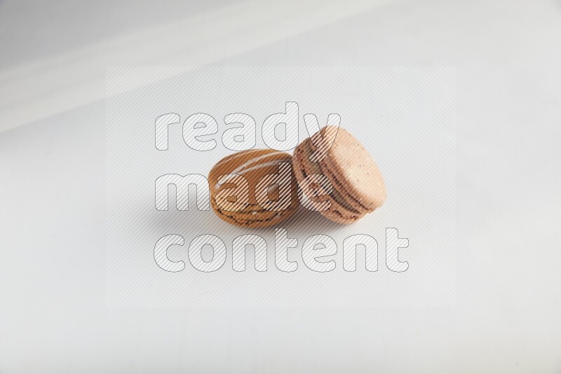 45º Shot of of two assorted Brown Irish Cream, and Brown Hazelnuts macarons on white background
