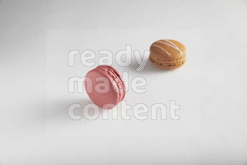 45º Shot of of two assorted Brown Irish Cream, and Pink Raspberry macarons on white background