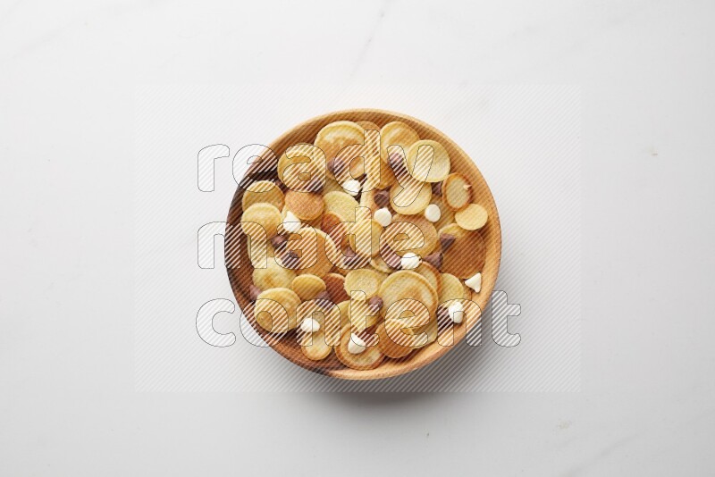 Top-view shot of mixed chocolate chips cereal pancakes in a round bowl on white background