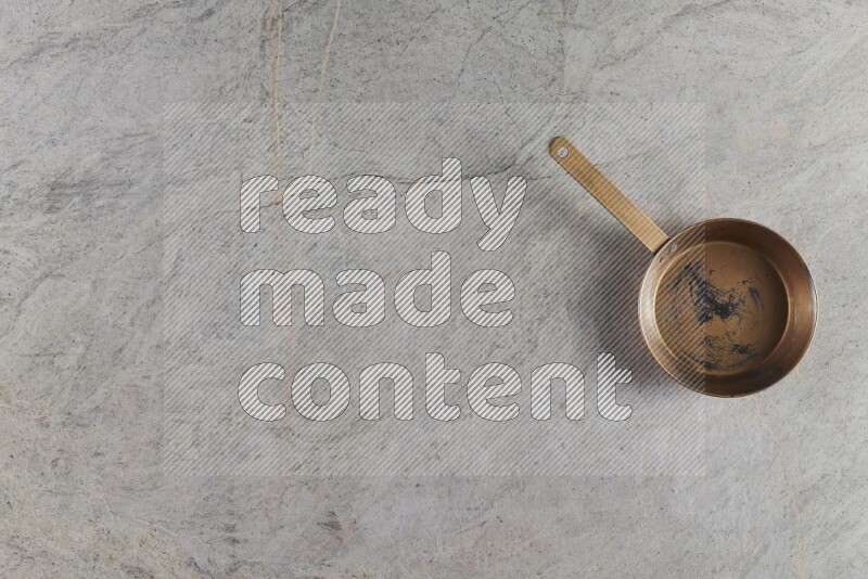 A small copper pan on grey marble background