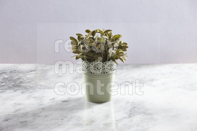 Artificial plant in green decorative pot on grey marble background