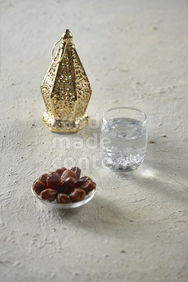 A golden lantern with different drinks, dates, nuts, prayer beads and quran on textured white background