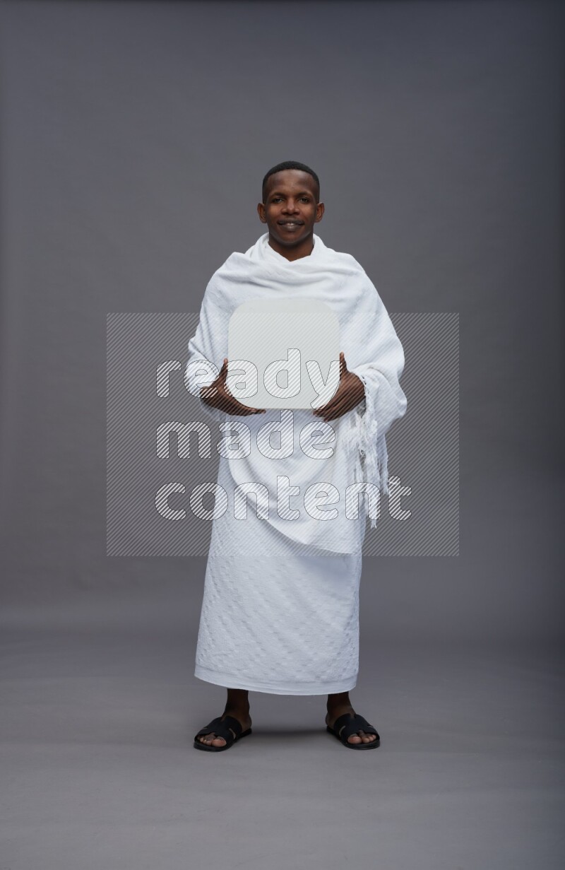 A man wearing Ehram Standing holding social media sign on gray background
