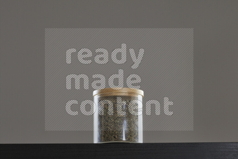 Dried basil in a glass jar on black background