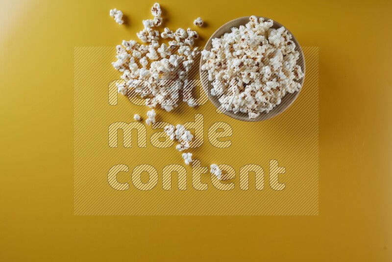 A multicolored ceramic plate full of popcorn with popcorn beside it on a yellow background in different angles