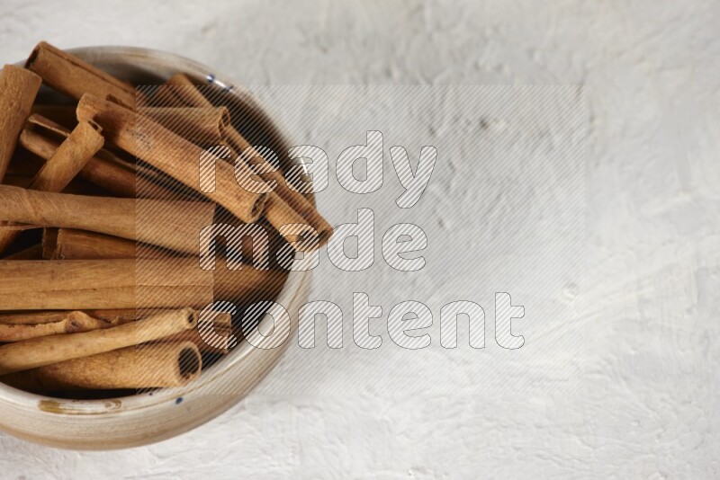 Cinnamon sticks in a ceramic bowl in different angles on white background