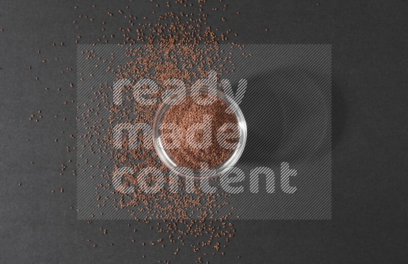 وعاء زجاجي ممتلئ ببذور حب الرشاد محاط بالبذور على أرضية سوداء