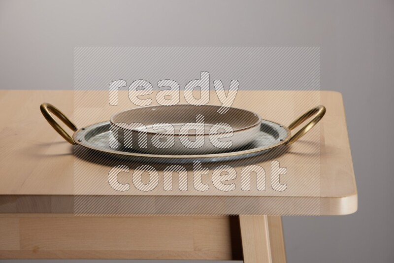 multicolored plate placed on a rounded stainless steel tray with golden handels on the edge of wooden table