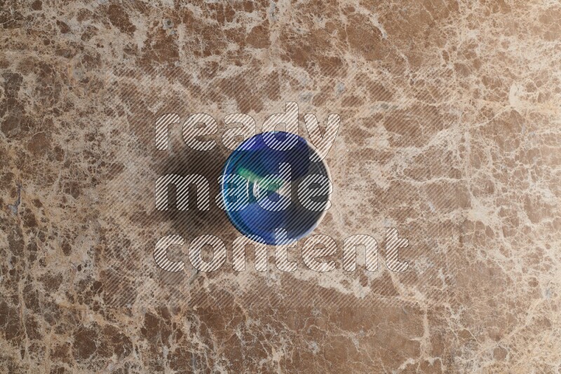 A multicolored pottery bowl on beige marble background