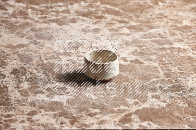 A beige pottery bowl on beige marble background