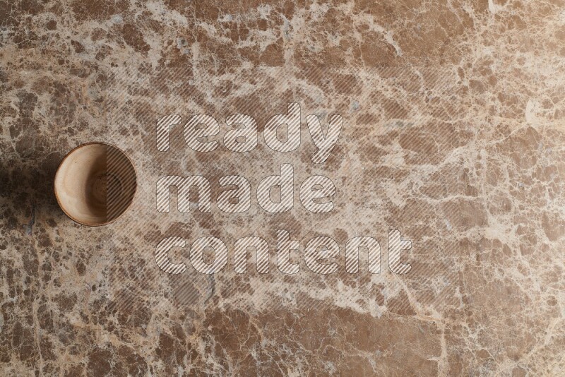 A pottery cup on beige marble background