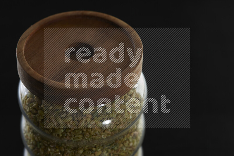 Freekeh in a glass jar on black background