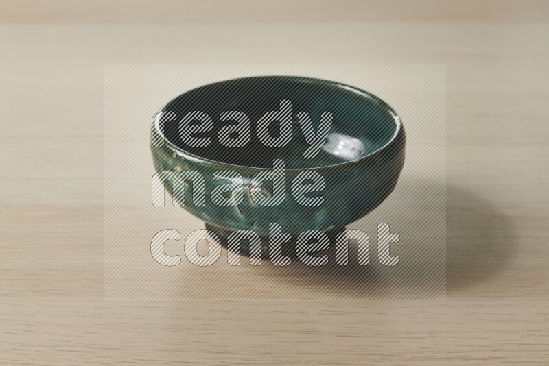A dark green pottery bowl on light wooden background