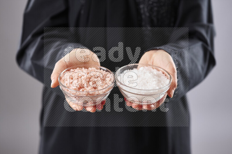 Woman in abaya holding different kinds of spices in different positions