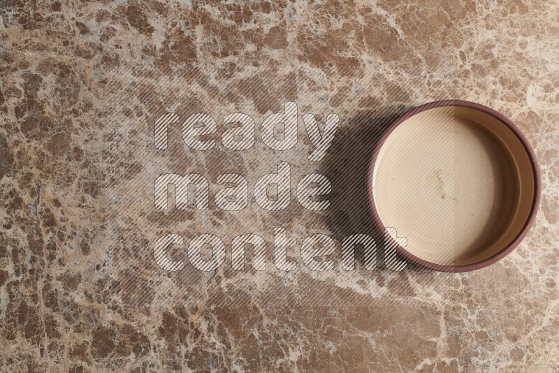 A beige pottery oven plate on beige marble background