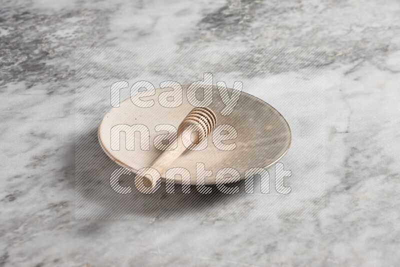 Multicolored pottery plate with wooden honey dipper in it on grey marble background