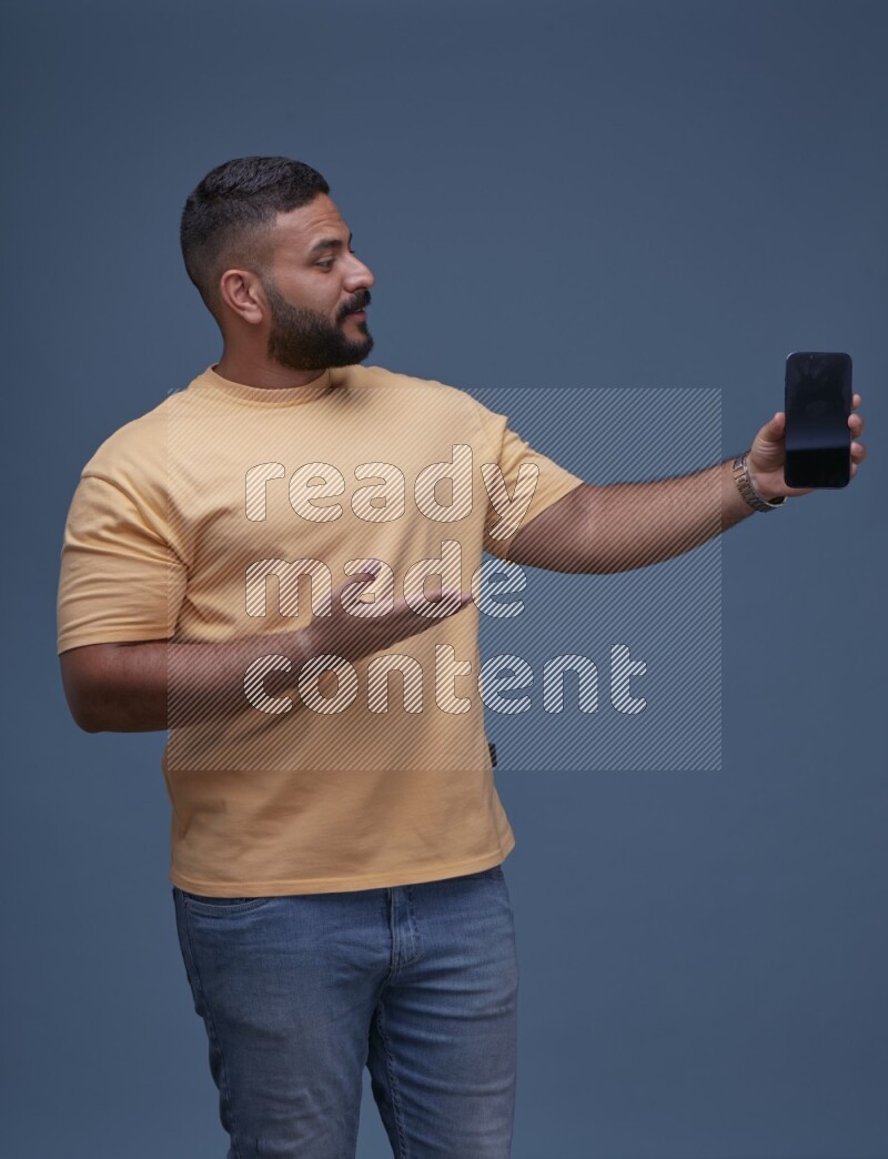 A man Showing His Smart Phone on Blue Background wearing Orange T-shirt