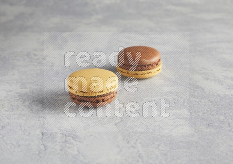 45º Shot of two Yellow and Brown Chai Latte macarons r on white  marble background