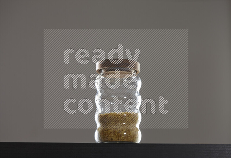Coarse bulgur in a glass jar on black background