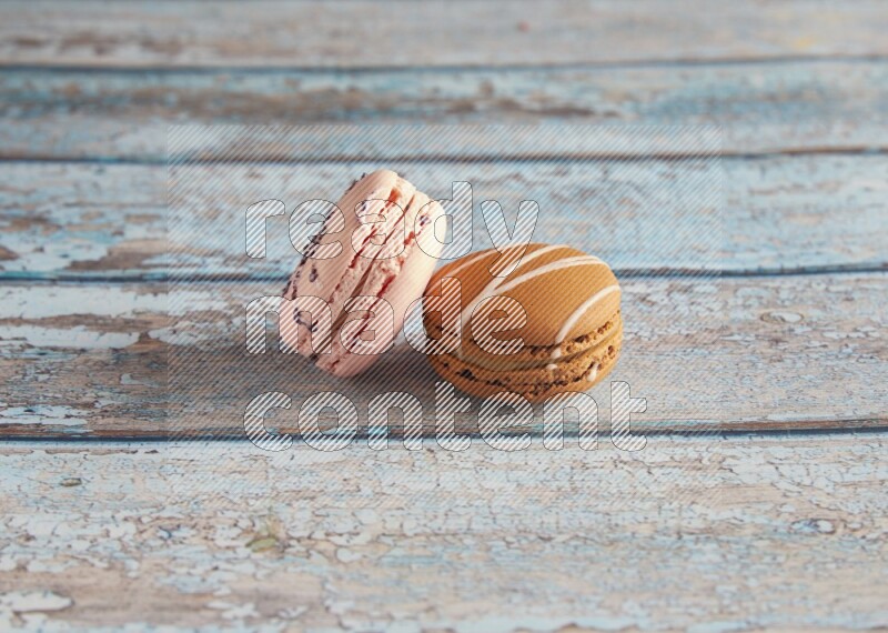 45º Shot of of two assorted Brown Irish Cream, and pink orange blossom  macarons on light blue background