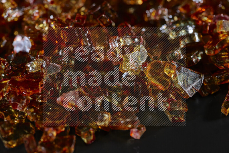 Transparent orange fragments of glass scattered on a black background