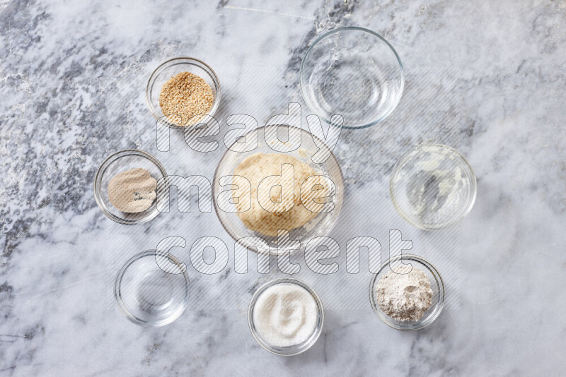 Kahk step by step with its ingredients ghee, sugar, flour, sesame, yeast, water and kahk flavor on grey marble background