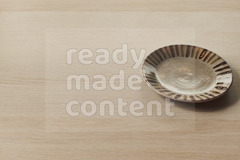 A multicolored pottery plate on light wooden background