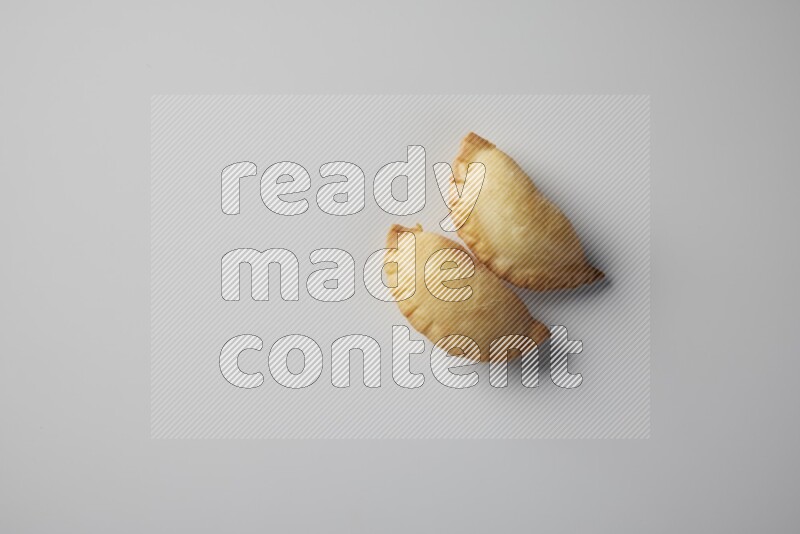 Two fried sambosa from a top angle on a white background