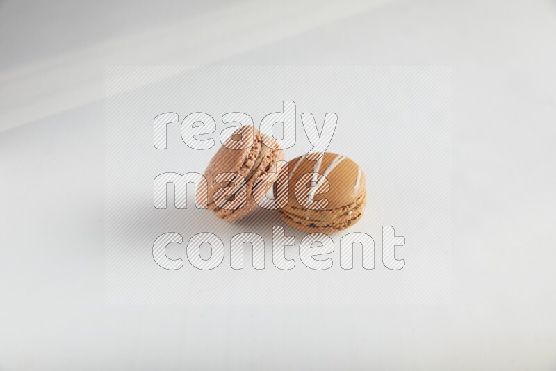 45º Shot of of two assorted Brown Irish Cream, and Brown Hazelnuts macarons on white background