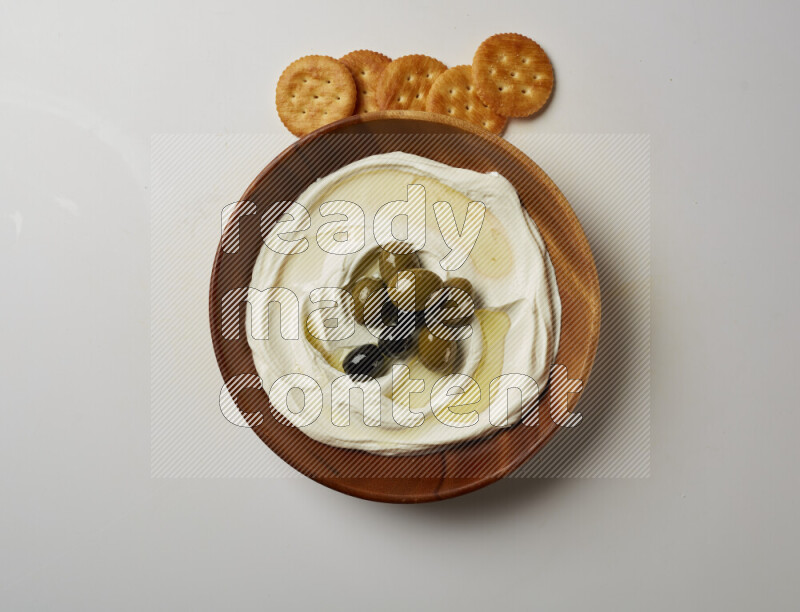 Lebnah garnished with whole olives in a wooden plate on a white background