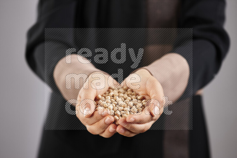 Woman in abaya holding different kinds of legumes in different positions