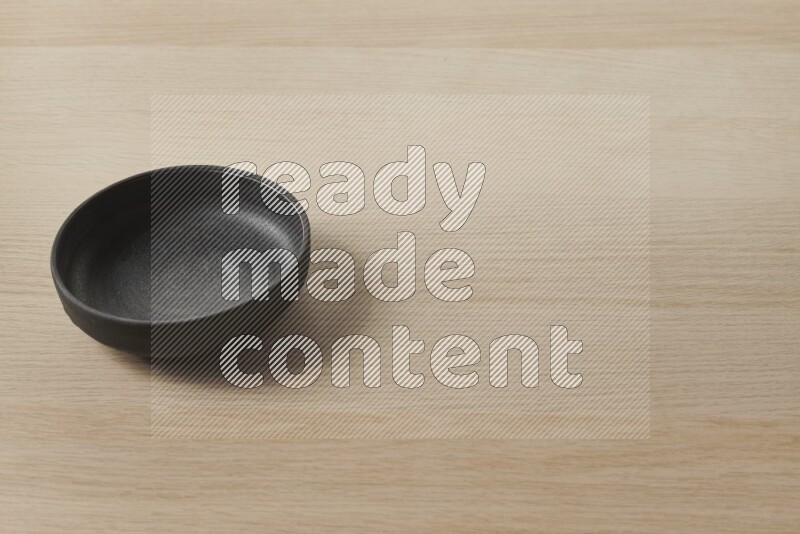A black pottery bowl on light wooden background