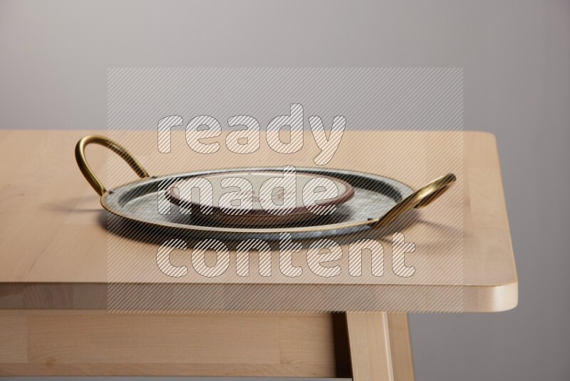 multicolored plate placed on a rounded stainless steel tray with golden handels on the edge of wooden table
