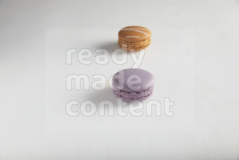 45º Shot of of two assorted Brown Irish Cream, and Purple Blueberry macarons on white background
