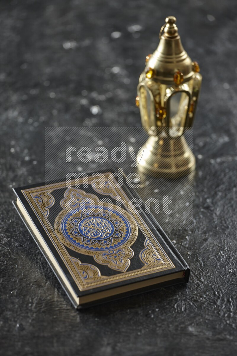 A golden lantern with different drinks, dates, nuts, prayer beads and quran on textured black background