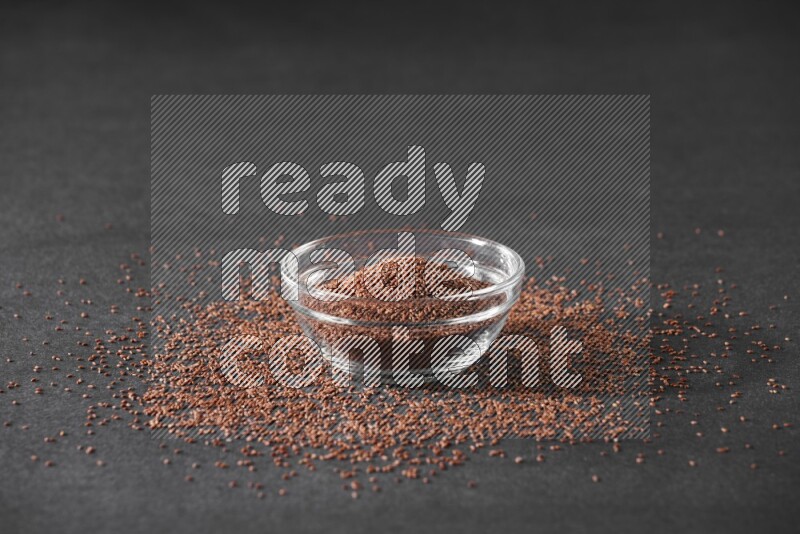 وعاء زجاجي ممتلئ ببذور حب الرشاد محاط بالبذور على أرضية سوداء