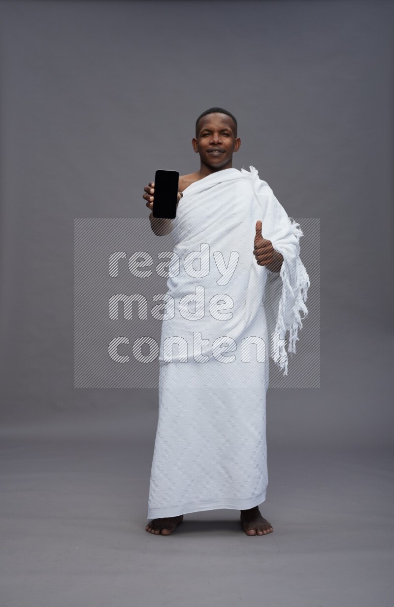 A man wearing Ehram Standing showing phone to camera on gray background