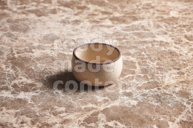 A beige pottery oven bowl on beige marble background