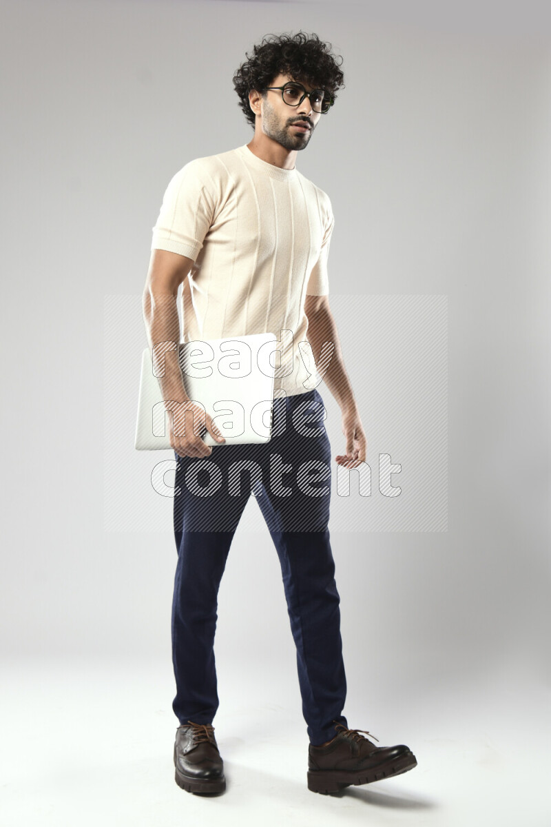 رجل يرتدي ملابس كاجوال يحمل لاب توب علي خلفية بيضاء