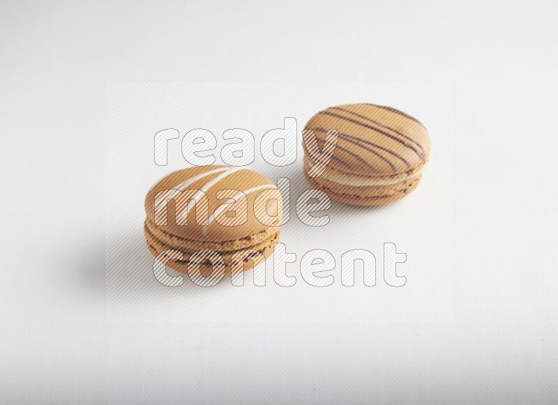 45º Shot of of two assorted Brown Irish Cream, and light brown  Almond Cream macarons on white background