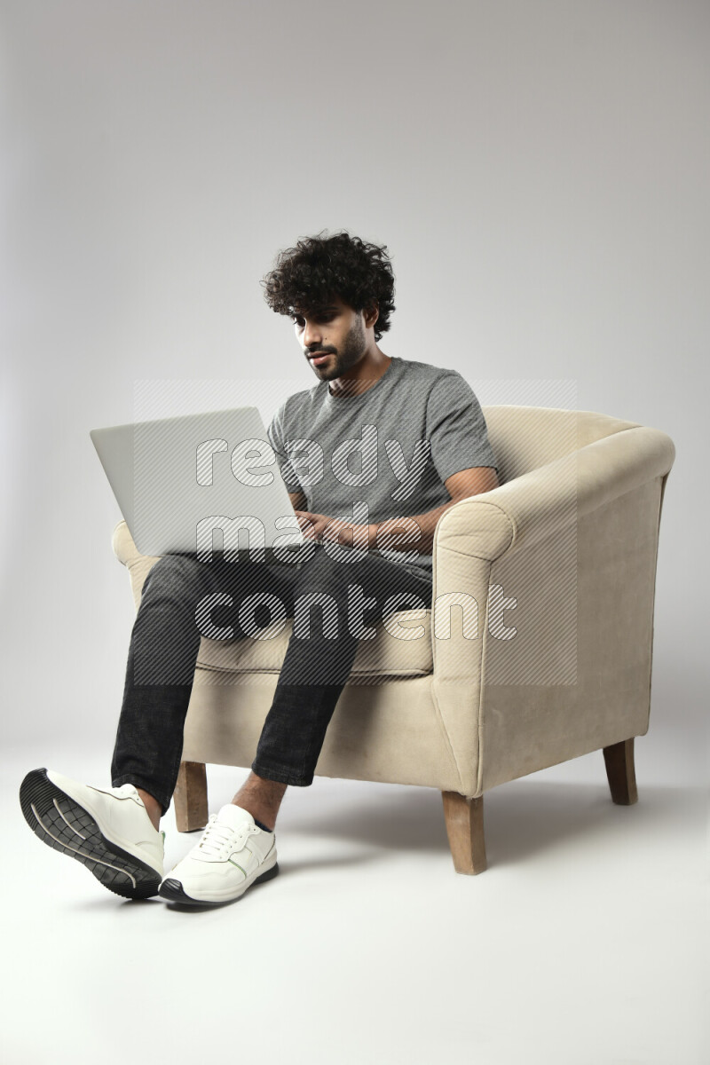 A man wearing casual sitting on a chair working on a laptop on white background