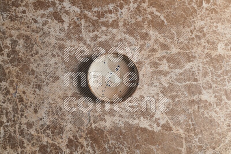 A multicolored pottery bowl on beige marble background