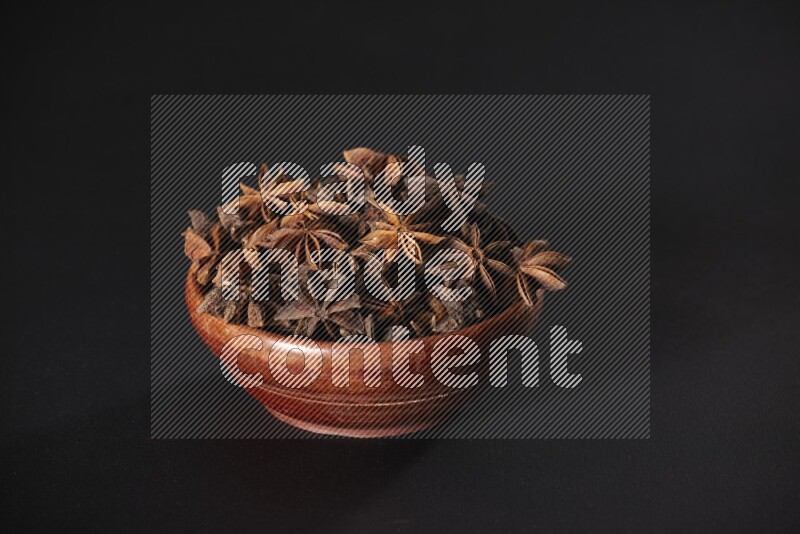 Star Anise in a wooden bowl on black flooring