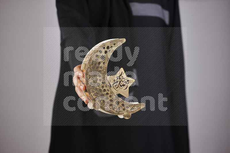A woman in black abaya holding different ramadan lanterns in different positions