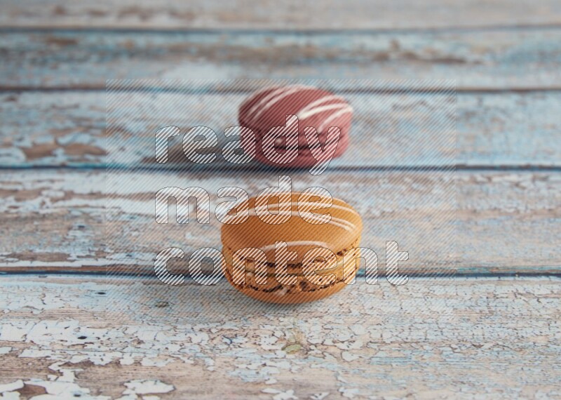 45º Shot of of two assorted Brown Irish Cream, and Red Poppy Flower macarons  on light blue background